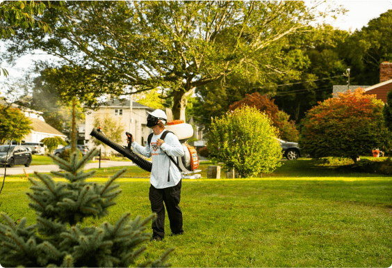 Man spraying for pests outside in a well manicured yard.